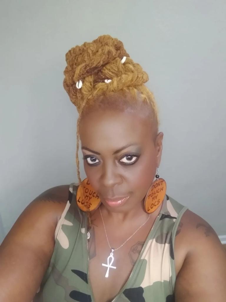 Golden loc bun updo with cowrie shells and camo top