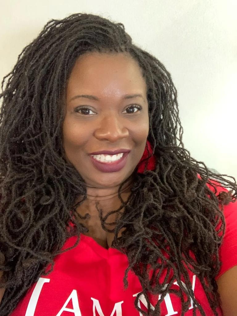 Long flowing locs in red shirt smiling