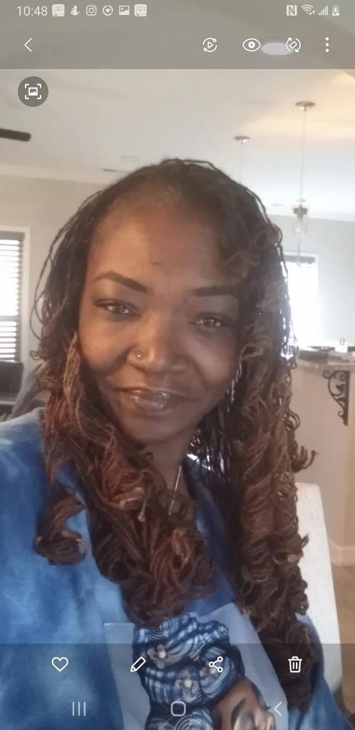 Curly twisted locs in blue tie-dye top home selfie